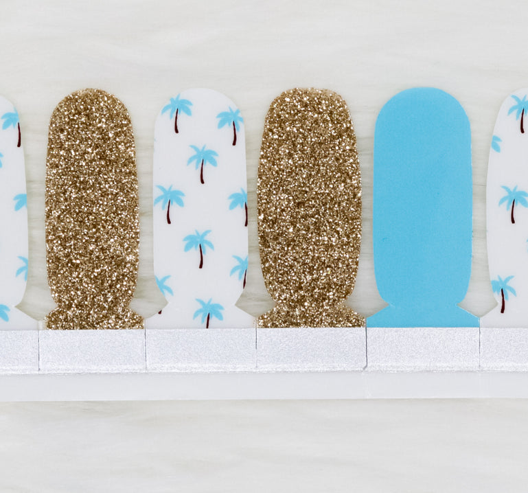 Light blue nail wraps with white nail wraps and blue palm trees. Also includes a gold glitter accent nail
